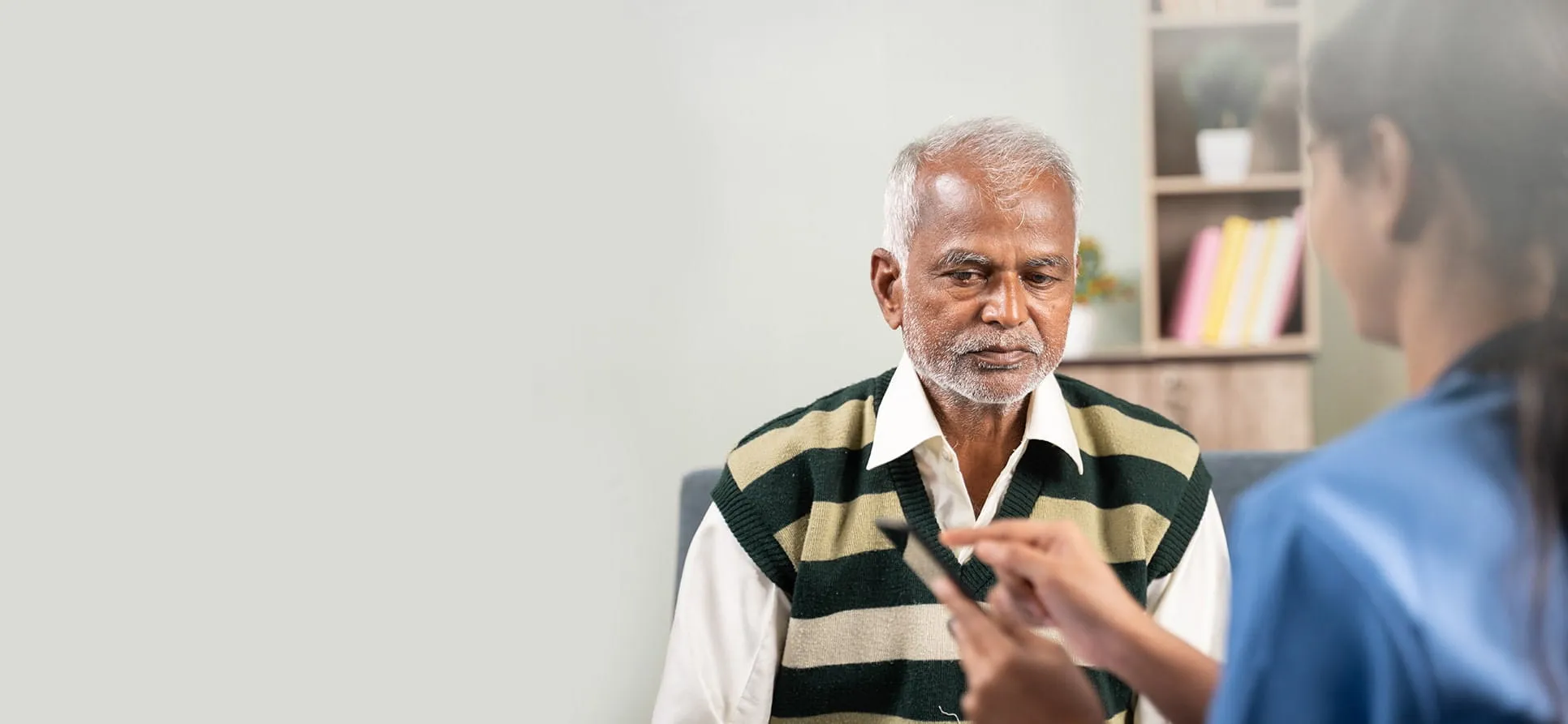 ক্লিনিকের কর্মী বয়স্ক রোগীর সঙ্গে নোট নিচ্ছেন